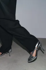 Sandalias plateadas de piel metalizada con puntera abierta, tiras cruzadas y cierre con tira trasera elástica. Tacón fino de 9,5 cm.