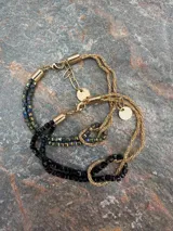 Pulsera de oro de 18k con diseño de cadena tipo serpiente doble y un nudo central decorativo. Cuenta con cierre de mosquetón y cadena de alargue con placa grabada.