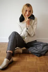 Chaqueta corta color beige con cuello de piel sintética negra, cierre frontal de botones y bolsillos laterales.