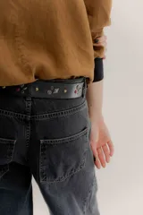 Cinturón de cuero marrón con hebilla negra y detalles metálicos en forma de rosas y rombos.