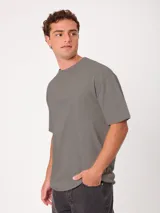 Remera holgada Rusty color gris con lavado ácido, cuello ancho y pequeño estampado frontal a la altura del pecho.