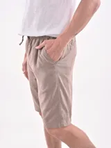 Bermuda color beige con cintura elástica y cordón ajustable, bolsillos laterales y corte por encima de la rodilla.