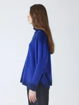 Suéter de tejido de punto con efecto degradado, pasando de gris oscuro a gris medio. Presenta cuello alto y mangas largas con puños acanalados.