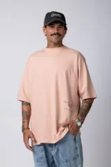 Remera blanca de corte oversize con cuello redondo y mangas cortas. Presenta un pequeño estampado tipográfico en la parte inferior frontal y un diseño gráfico de mayor tamaño en la espalda.