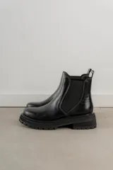 Botas tipo Chelsea de cuero con acabado vintage, diseño de caña media con paneles elásticos laterales y suela track robusta.