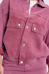 Campera de jean lavada color rosa, corte bomber con cuello clásico, cierre frontal con botones metálicos, mangas largas con puños abotonados, bolsillos frontales con solapa y cintura elastizada.