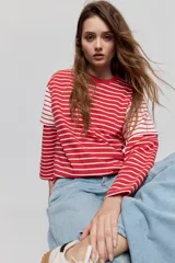 Remera de manga larga a rayas rojas y blancas, con diseño holgado y cuello redondo.