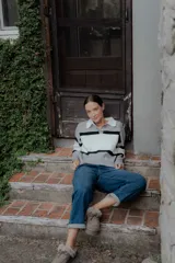 Sweater tipo polo de punto con diseño color block en tonos gris, blanco y negro. Presenta cuello camisero en contraste, cierre frontal con botones y mangas largas.