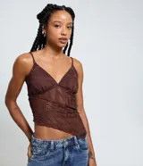 Top de encaje marrón oscuro con patrón geométrico calado, escote en V y breteles finos ajustables. El ruedo es asimétrico y tiene forro solo en la zona del busto.