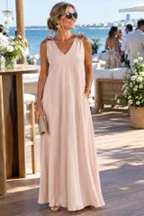 Vestido largo color beige de líneas simples, con escote en V, sin mangas y apliques de flores decorativas en los breteles. Cuenta con bolsillos laterales.