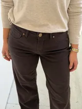 Pantalón de jean color chocolate, de corte recto y tiro medio, con costuras laterales visibles y cierre frontal con botón y cremallera.