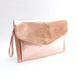 Sobre tipo clutch color rosa metalizado, con cierre de solapa imantada y lazo de muñeca.