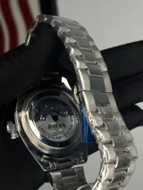 Reloj Rolex Datejust plateado con esfera negra, indicador de fecha y malla de acero inoxidable.