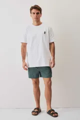 Remera blanca de manga corta y corte holgado, con cuello redondo y pequeño estampado en el pecho.