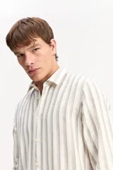 Camisa de manga larga color beige, de tejido texturado con cierre frontal de botones y cuello camisero clásico.