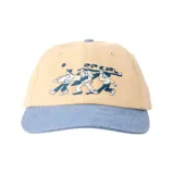 Gorra de visera curva con diseño bicolor, cuerpo en color beige y visera en azul. Presenta un bordado frontal con ilustración artística y el texto Rip Curl.