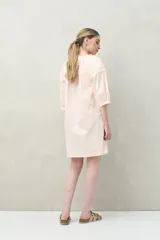 Vestido corto negro con bordado floral blanco, escote redondo con abotonadura frontal y mangas 3/4 abullonadas con pliegues en los hombros.