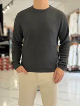 Buzo de hilo gris oscuro con diseño de tejido acanalado, cuello redondo y mangas largas.