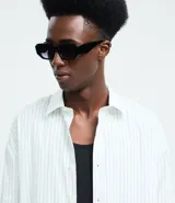 Camisa de manga larga con diseño de rayas verticales, cuello clásico y cierre frontal con botones. Confeccionada en una mezcla de algodón, poliamida y elastano, presenta una estampa gráfica en la espalda con la frase Echoes of a Restless Beat.