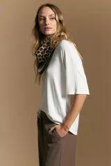 Remera de calce relajado con silueta fluida, confeccionada en tejido de viscosa con elastano. Presenta cuello redondo, mangas cortas y un diseño minimalista de caída suave.