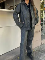 Campera de cuero sintético color gris oscuro, con cuello camisero, cierre frontal con cremallera dorada y bolsillos laterales.