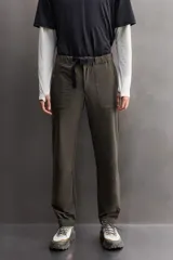 Pantalón largo color verde oscuro, de corte slim fit y tiro medio. Confeccionado en tejido técnico elástico, con cintura ajustable mediante cinturón con hebilla plástica. Presenta bolsillos laterales con cierre de cremallera oculta y bolsillo trasero con cierre de cremallera oculta.