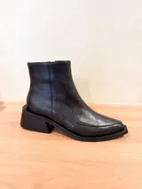 Bota corta de cuero vacuno color negro, con cierre lateral interno, taco cuadrado de madera y punta fina.