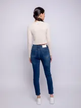 Pantalón de jean chupín color azul medio, con cinco bolsillos, presillas, botón y cierre metálico.