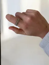 Anillo triple de acero quirúrgico, compuesto por tres bandas finas con texturas diferentes: una lisa, una con pequeñas esferas y una con diseño de bolitas.