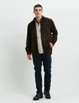 Sobrecamisa de pana color marrón, con manga larga, cierre frontal con botones y dos bolsillos frontales con solapa y botón.