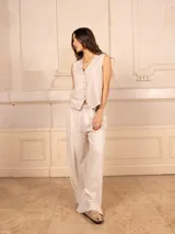 Chaleco blanco de lino con corte sastrero, cuello en V y cierre frontal con botones.