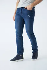 Pantalón de jean corte regular, color azul oscuro, con diseño de cinco bolsillos, pasacintos y detalles de roturas localizadas en la parte frontal.
