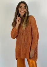 Buzo color ámbar de tejido calado con lurex, escote en V y mangas largas.