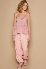 Top de tirantes finos color rosado, con escote en V y pechera de encaje floral. Cuenta con un detalle de volado en el ruedo y un acabado de lavado vintage.