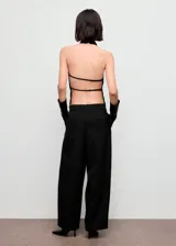 Top negro sin mangas de cuello halter drapeado, con bajo asimétrico y espalda abierta con tiras.