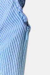 Vestido midi confeccionado en mezcla de viscosa con estampado de rayas verticales en celeste y blanco. Posee escote en pico con abertura ajustable mediante lazada en el pecho, tirantes anchos y cierre lateral con cremallera oculta. El diseño cuenta con aberturas en el bajo frontal y posterior.