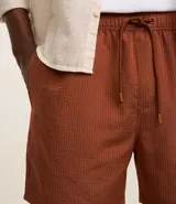 Bermuda de baño color beige, confeccionada en tejido ana ruga texturizado. Tiene lazo en la cintura, bolsillos laterales y un bolsillo trasero.