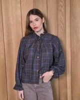 Camisa de manga larga con estampado de cuadros en tonos azules y rojizos. Presenta un cuello alto con volados y puños elásticos con detalle de volado en el extremo. Cierre frontal con botones ocultos.