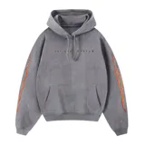Canguro gris con capucha y cordones ajustables, de corte holgado. Presenta un estampado frontal con la frase 'Hoy ando mágico' y detalles de llamas en ambas mangas.
