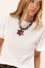 Blusa blanca de textura arrugada con cuello redondo y mangas cortas, de corte recto y estilo casual.