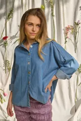 Camisa de denim suave, de corte oversize, con mangas largas abombadas, puños doblados y cierre frontal con botones nacarados.