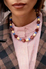 Collar corto compuesto por cuentas de cristal checo en tonos bordó, crema y azul, con diseño de formas geométricas y esféricas.