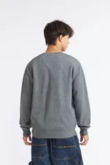 Buzo Quiksilver modelo Lavi de color gris melange, cuello redondo con detalle triangular en el escote y pequeño parche con logo en el pecho.