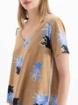 Remera marrón melange con estampa floral en tonos azules y negros, cuello en V y mangas cortas.