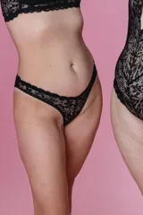 Bombacha de bikini tiro bajo/medio, color negro, confeccionada con tela que contiene fibra LYCRA® y frente de puntilla elastizada.