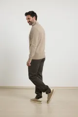 Sweater verde de punto inglés con cuello alto y cierre metálico frontal. Tiene mangas largas y terminaciones en punto canalé.