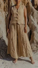 Conjunto de dos piezas compuesto por un chaleco sin mangas con cierre frontal de botones y un pantalón de pierna ancha con costuras verticales decorativas. Ambas prendas presentan un diseño holgado y fluido.