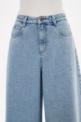 Pantalon de jean azul de corte ancho y tiro alto, con ruedo deshilachado.