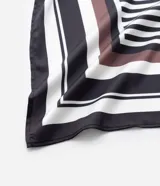 Pañuelo cuadrado de tela satinada con diseño geométrico de rayas y estampado de palmeras en tonos blanco, negro y marrón.
