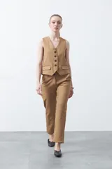 Chaleco sastrero color marrón oscuro, con escote en V, cierre frontal de botones y pinzas de entalle.